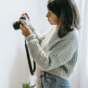 Young woman checking modern photo camera